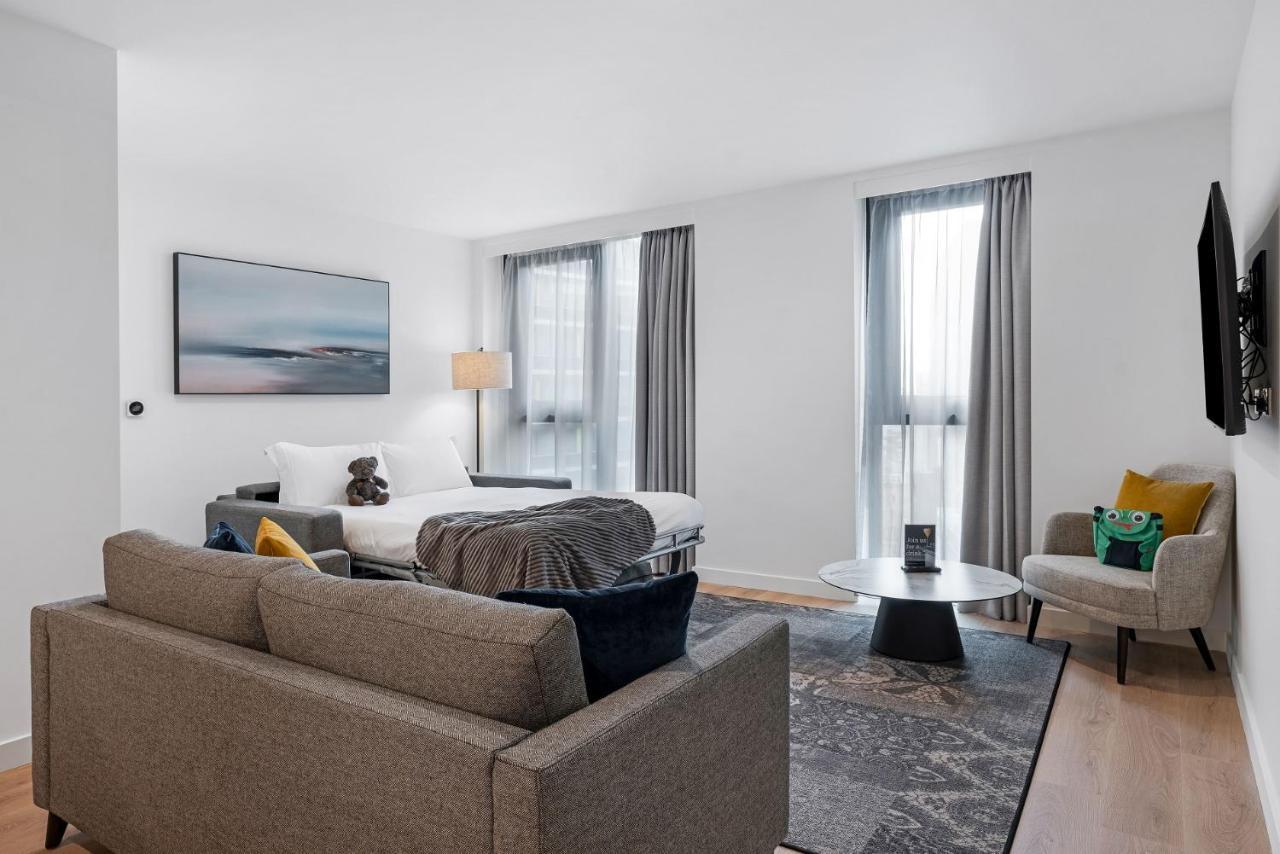 Citysuites 2 Aparthotel Salford  Exterior foto The photo shows a modern living space that incorporates a cozy and inviting atmosphere. It features a light-colored couch with colorful cushions, positioned in front of a coffee table. There's a comfortable armchair nearby, and a throw blanket is dra