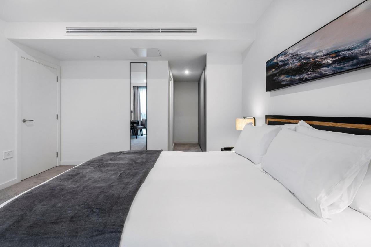 Citysuites 2 Aparthotel Salford  Exterior foto The photo shows a modern bedroom with a minimalistic design. In the foreground, there is a neatly made bed with white linens and a dark gray throw blanket. To the side, there is a bedside lamp and a piece of abstract artwork on the wall above the bed