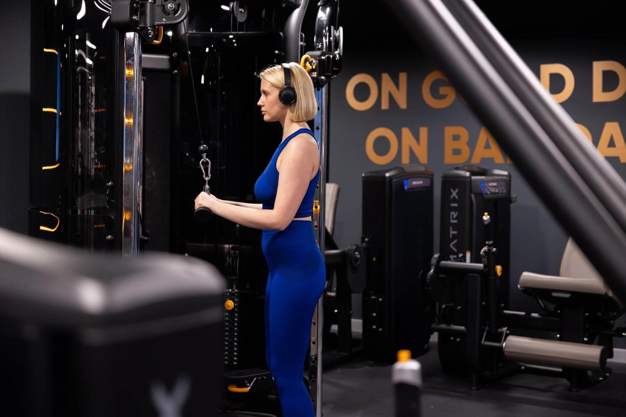 Citysuites 2 Aparthotel Salford  Exterior foto The photo shows a woman working out in a gym. She is wearing a blue athletic outfit and headphones while using a gym machine. The background features various other gym equipment and a wall with the words "ON GOOD ON BAD" displayed prominently. The se